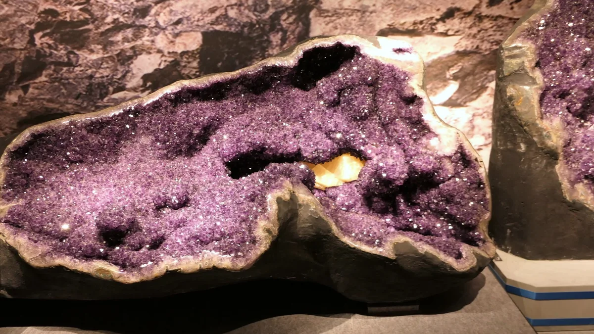 Aufgeschnittene Amethyst-Geode voller violetter Kristalle in einer Ausstellung